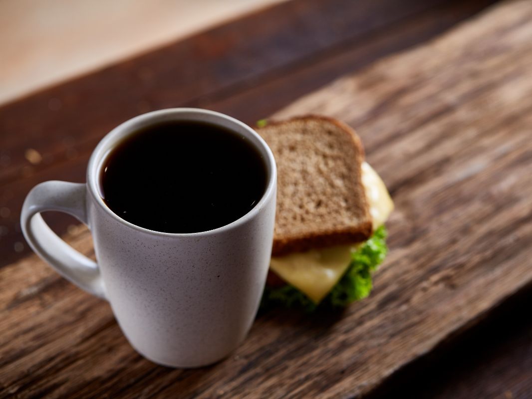 Taza de cafe junto a un sandwich